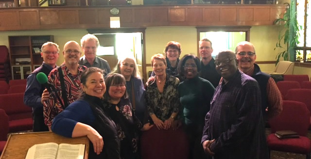 Group photo of Tapestry community members smiling together in a church or community center setting.